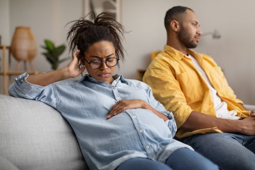 Marital Crisis. Unhappy Pregnant Black Wife Sitting Near Indifferent Husband After Quarrel At Home. Divorce During Pregnancy, Relationship Problems Concept.