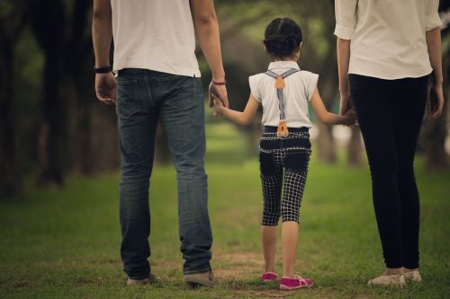 Daughter and parents holding hands in the park visual concept for family law blog: Divorce with Children: How to Tell Your Child about Divorce.