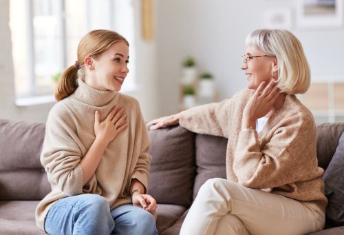 Young woman working on relationship with her mother-in-law while they are sitting on sofa. Visual concept for legal advice blog on maintaining a relationship with your ex-in-laws.