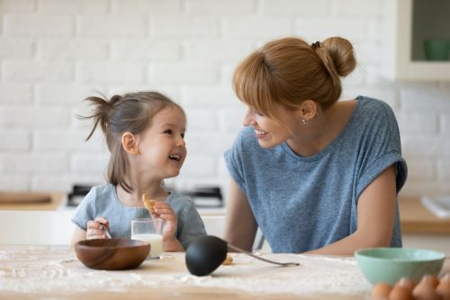 Smiling mother and daughter baking cookies standing at table in kitchen. Visual concept for family law blog on the subject of communication with your child through your divorce.