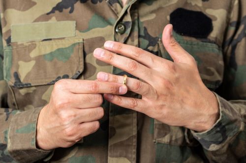 Hands of male soldier male who is removing his wedding ring. Visual concept for a military divorce blog.
