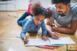 Black father and daughter lying in floor coloring. Concept for Missouri Court Holds Child Custody Sub-Issue Require a Childs Best Interests Determination