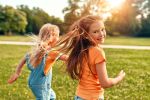 Two cute little children running and playing in the meadow in the park on a warm sunny day, having fun and enjoying nature on a day off. Visual concept for blog discussing Activities to Do with Your Child to Help Them Cope with Your Divorce.