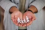 Close up of male hands holding paper cut out family. Visual concept for a blog discussing use of a collaborative approach in family law matters.